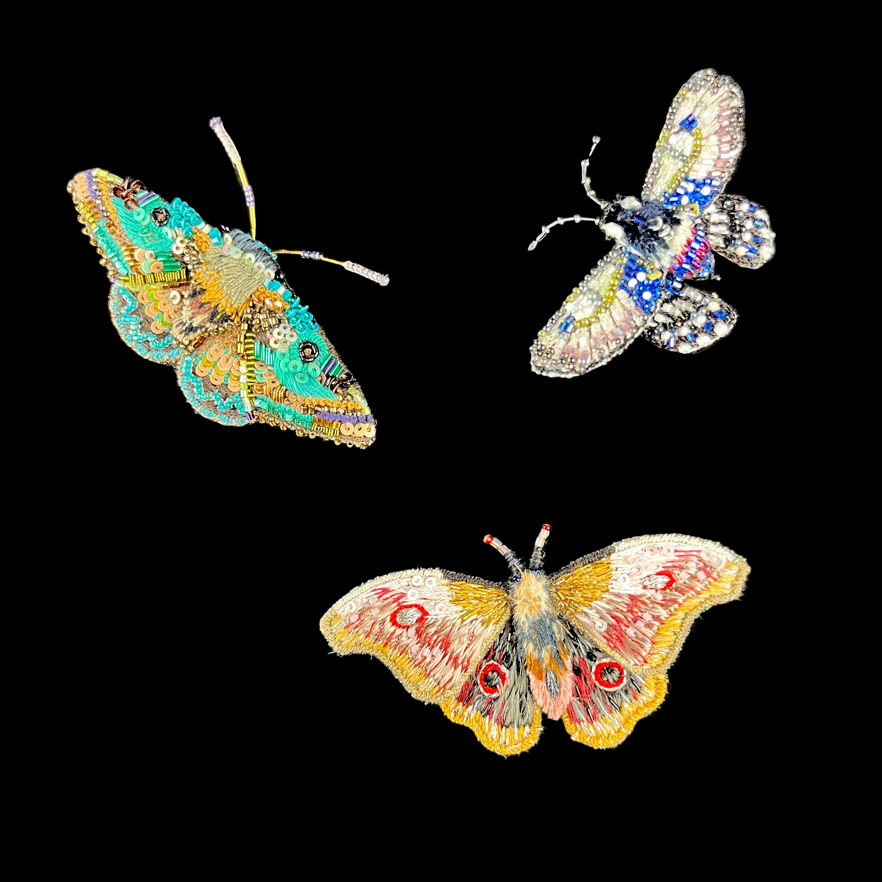 Three colorful butterfly brooches on black card backgrounds