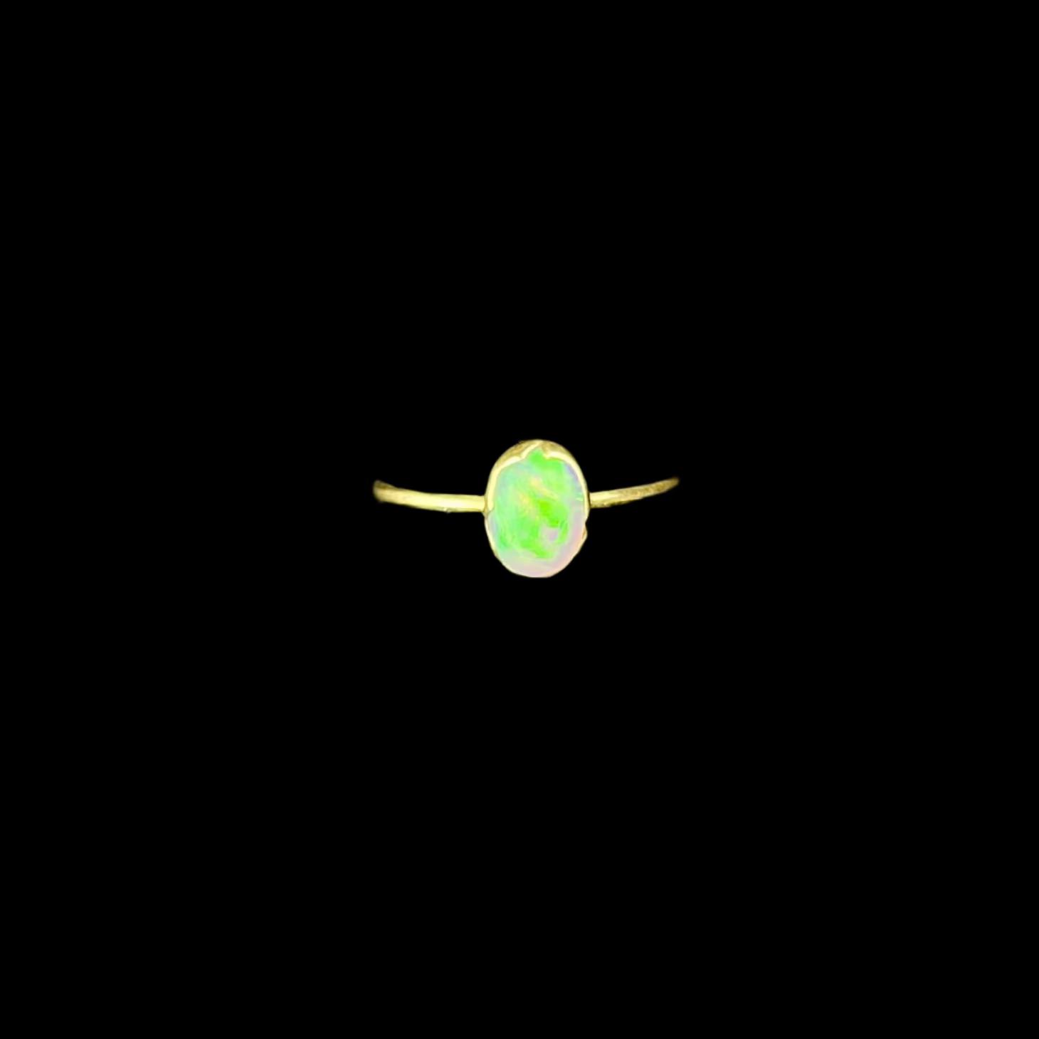 Ring with a green stone on a black stand against a dark background