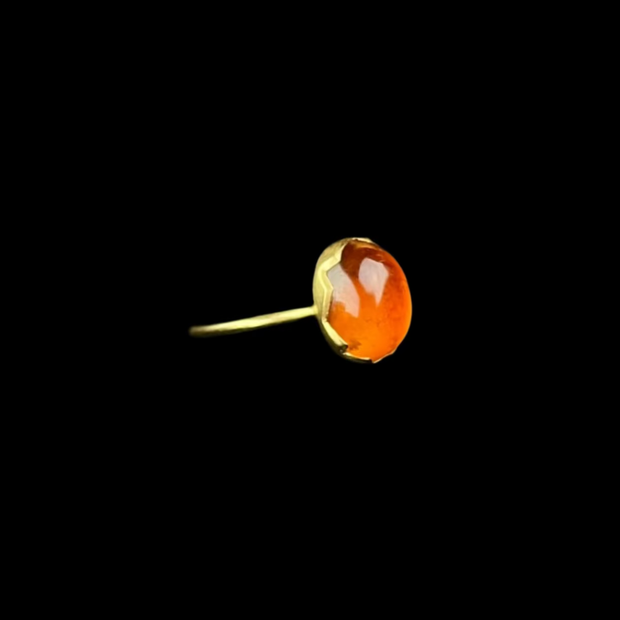 Gold ring with orange colored stone on black background