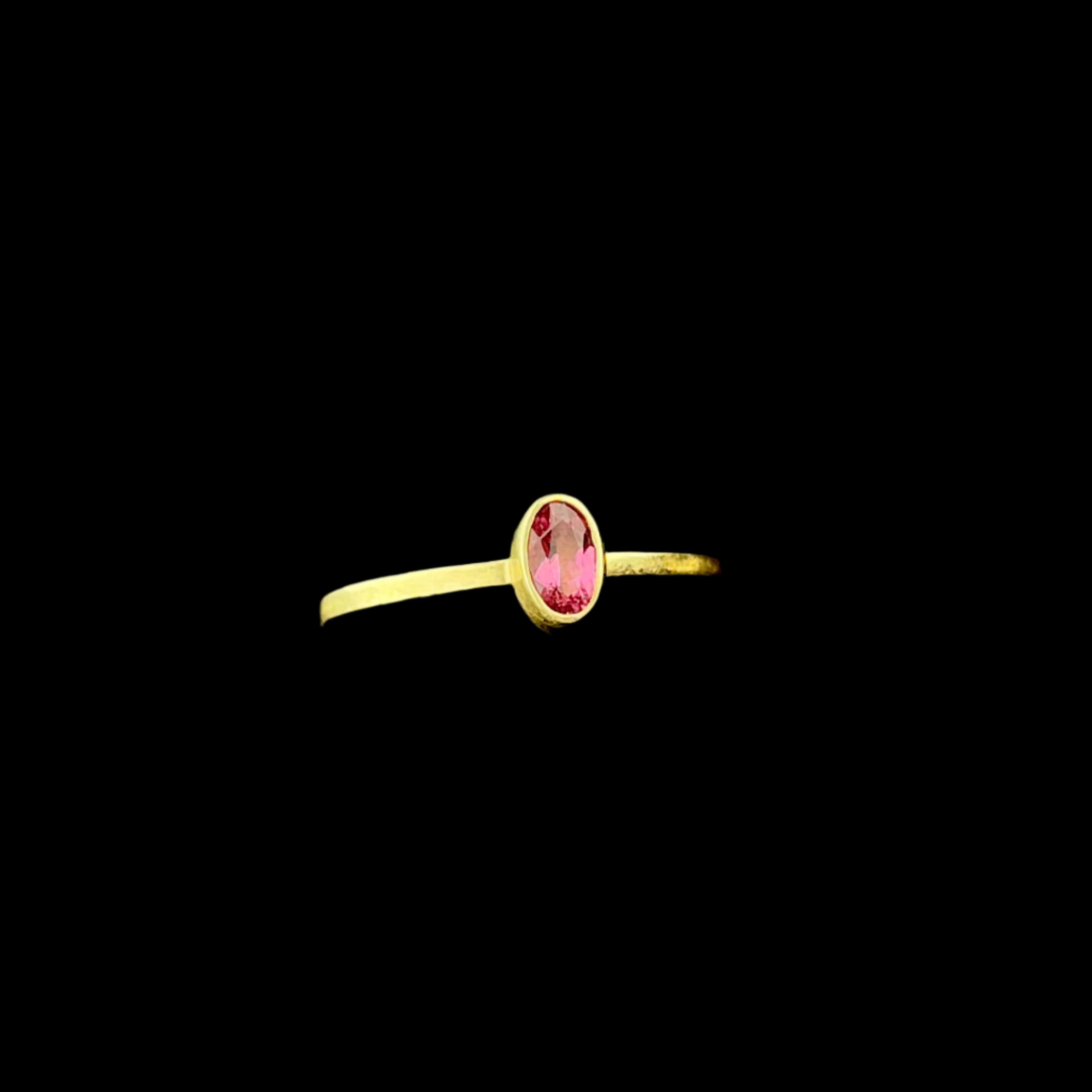 Gold ring with a pink gemstone on a dark background