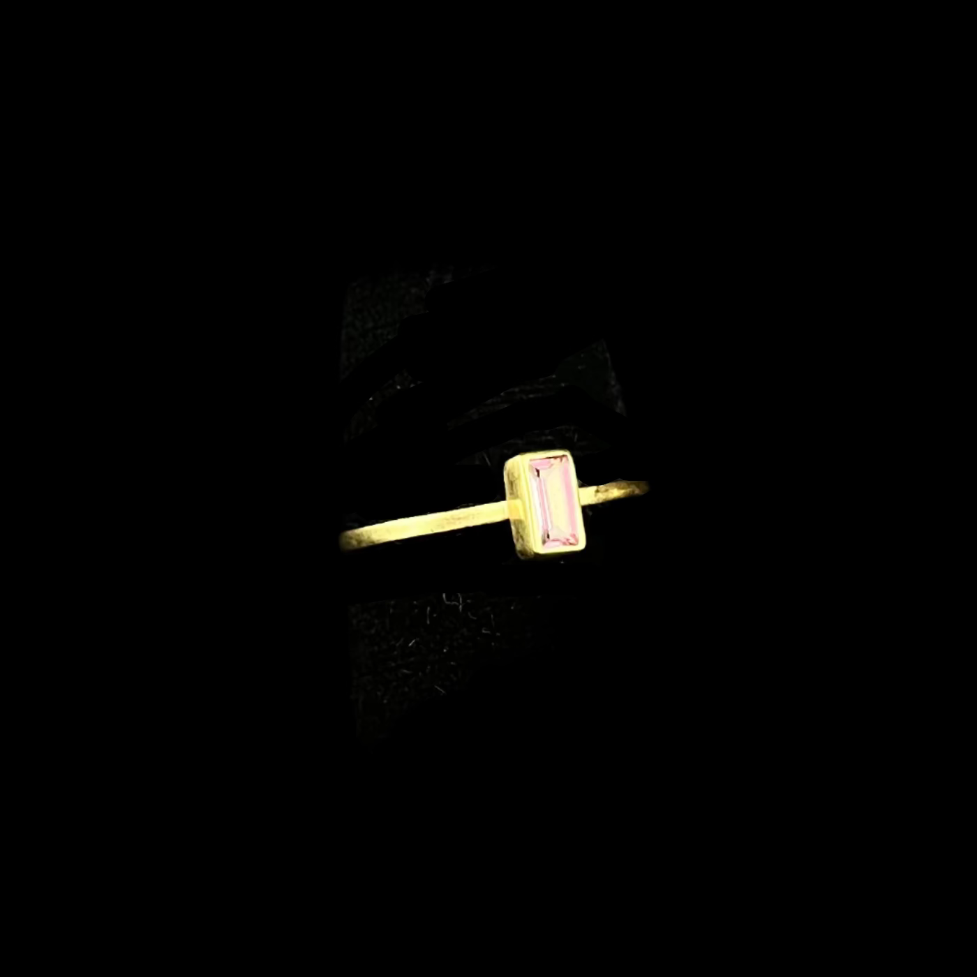 Gold ring with a pink gemstone on a black background