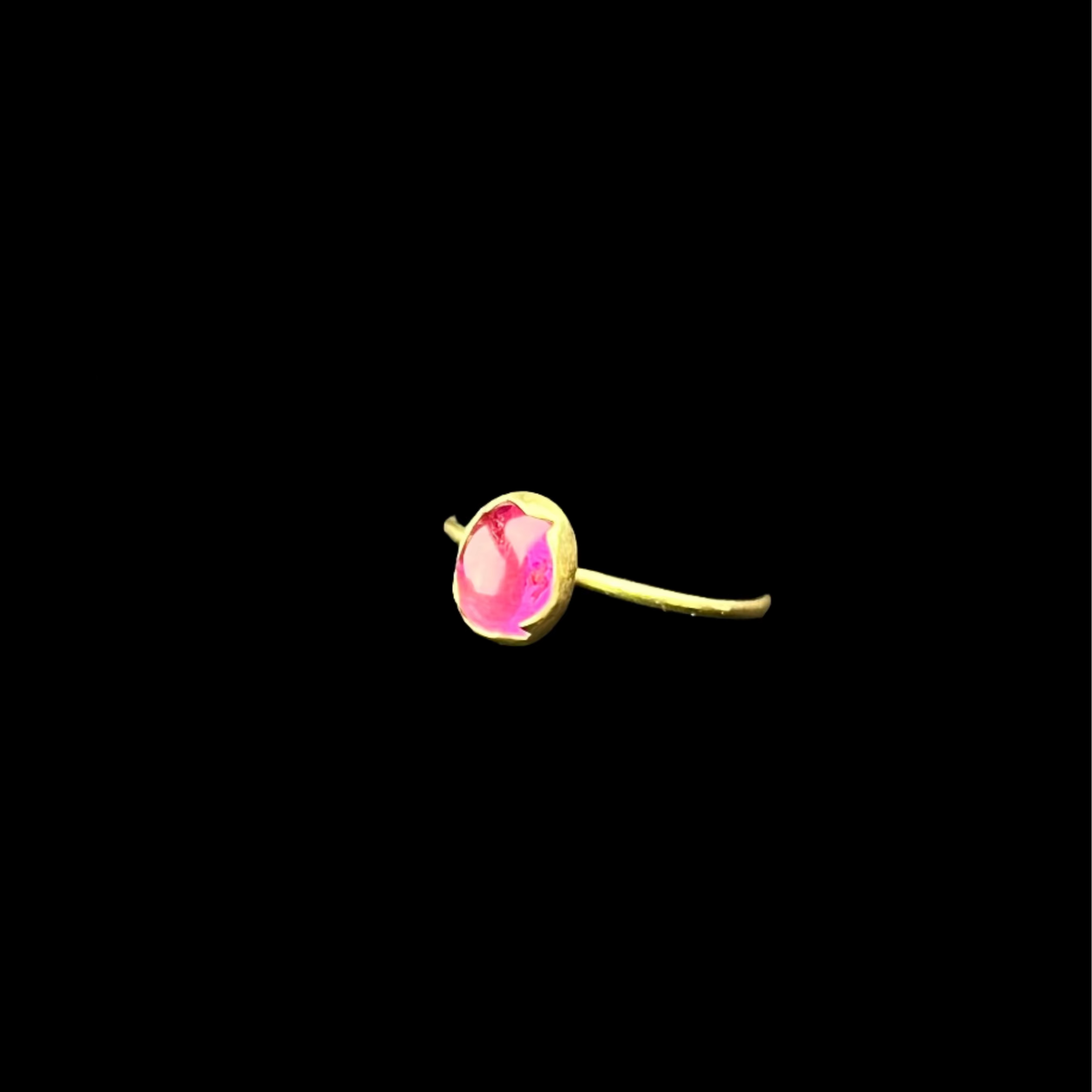 Gold rings with pink gemstones on a black surface