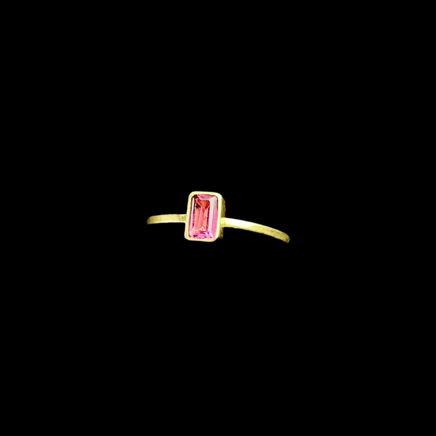 Gold ring with a pink gemstone on a dark background