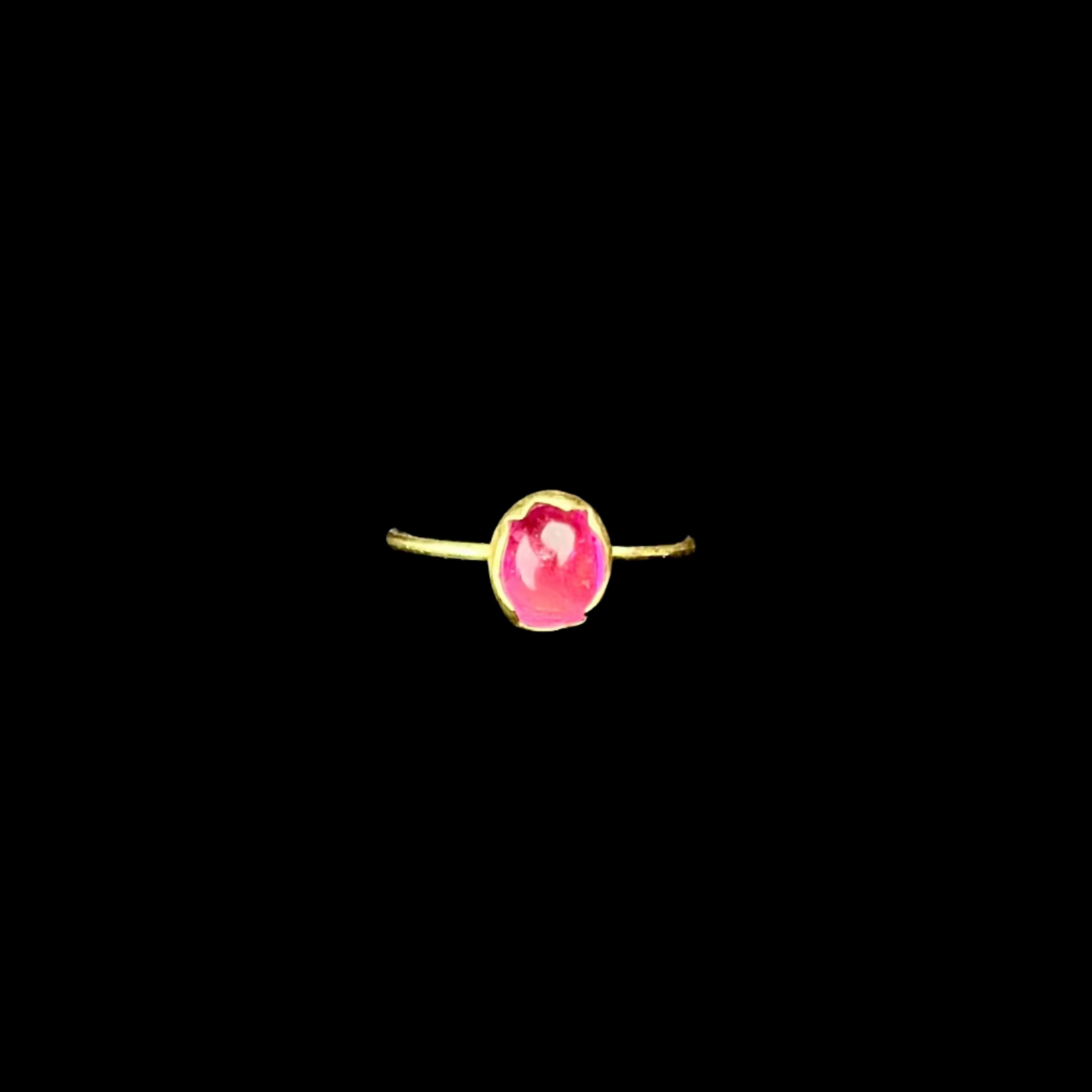 Ring with a pink gemstone on a black stand against a dark background