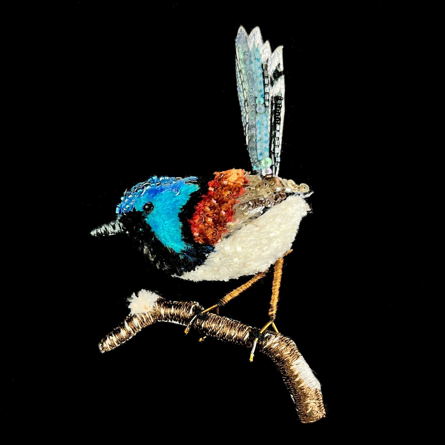Blue headed bird with a rust colored brown and grey wings and white body perched on brown branch with its tail in the air