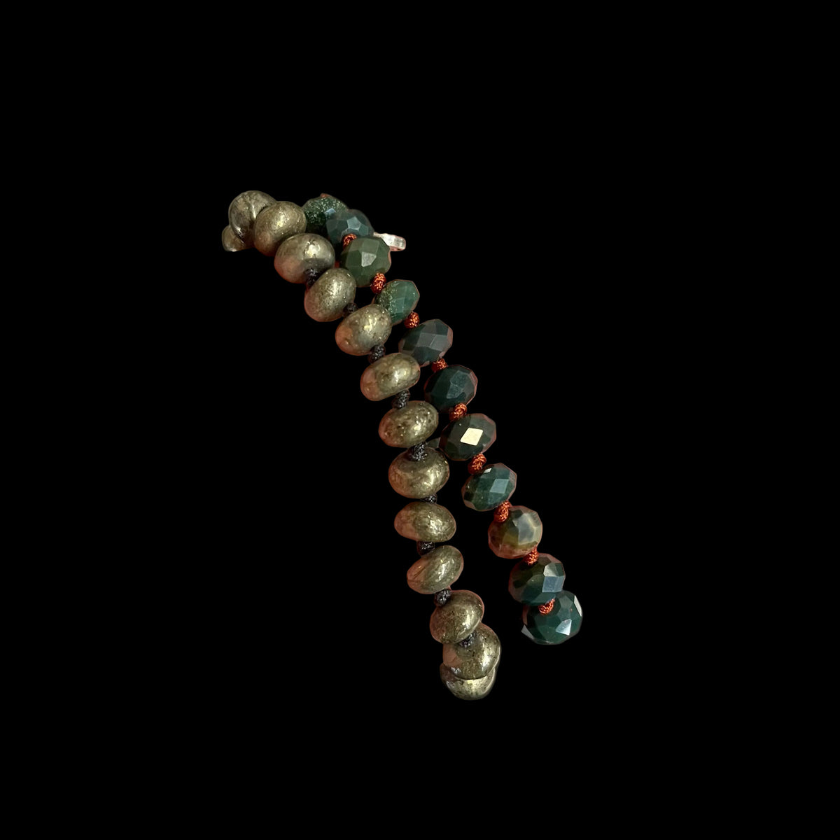 A close-up of two beaded bracelets. The bracelets feature faceted beads in metallic gold, deep forest green, and glossy black, separated by small copper-toned spacer beads.