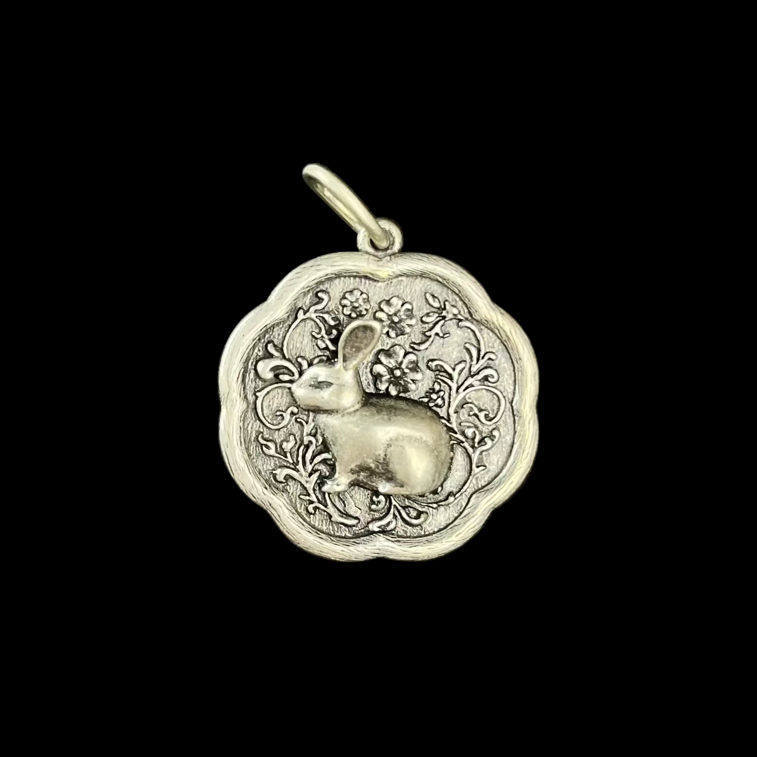 Silver pendant with a rabbit design on a black background