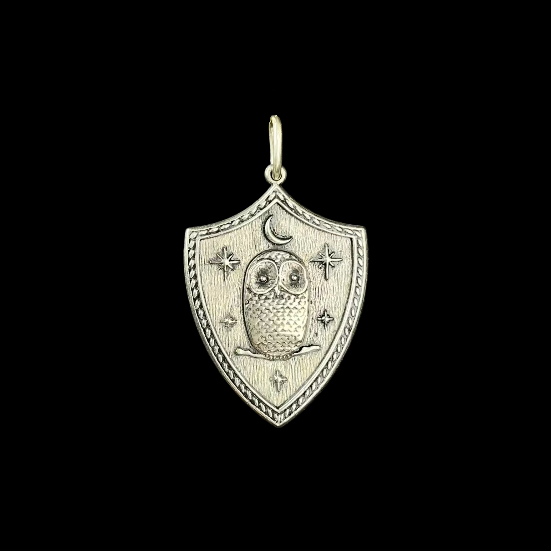 Silver pendant with owl design on a black background