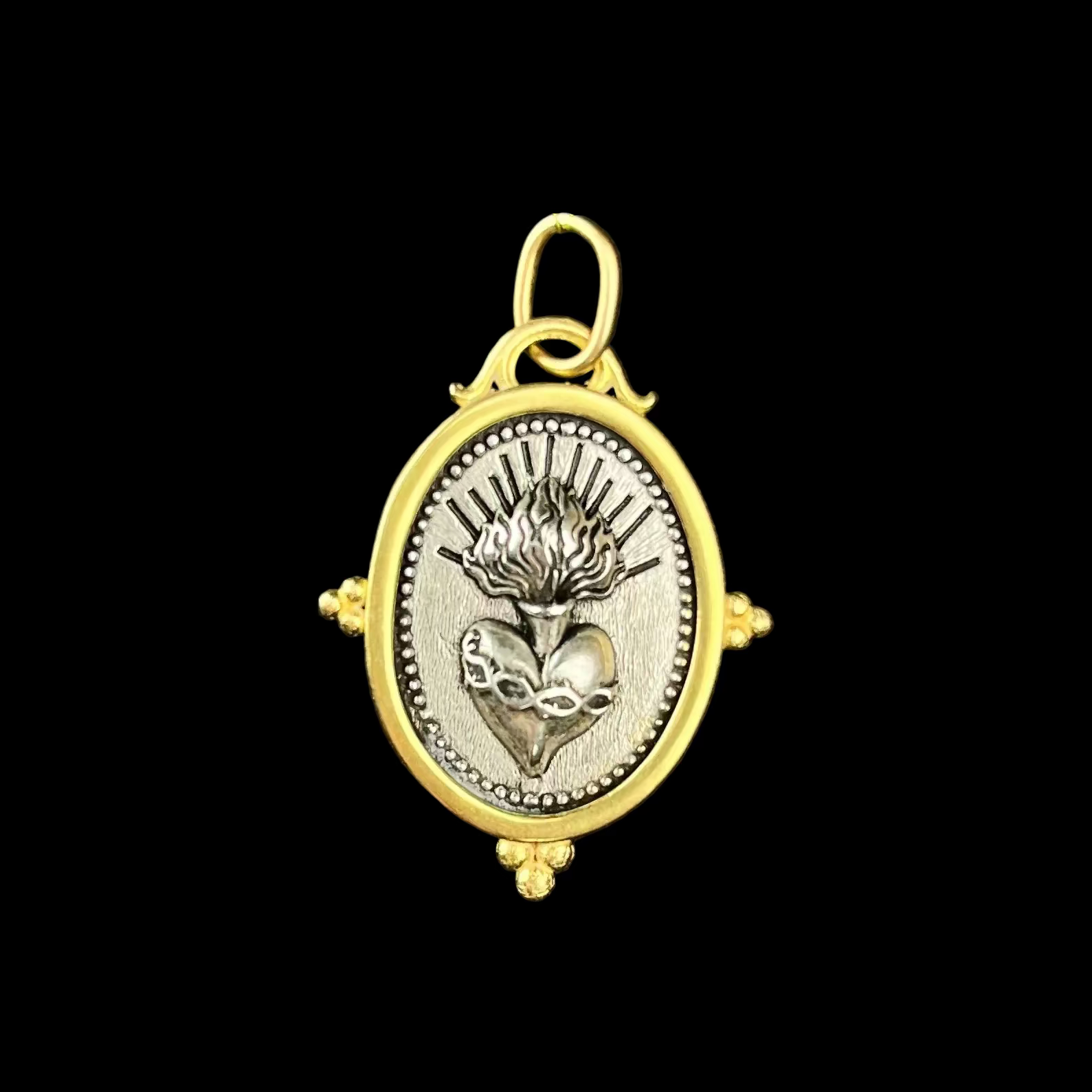 Gold and silver pendant with intricate design on a black background