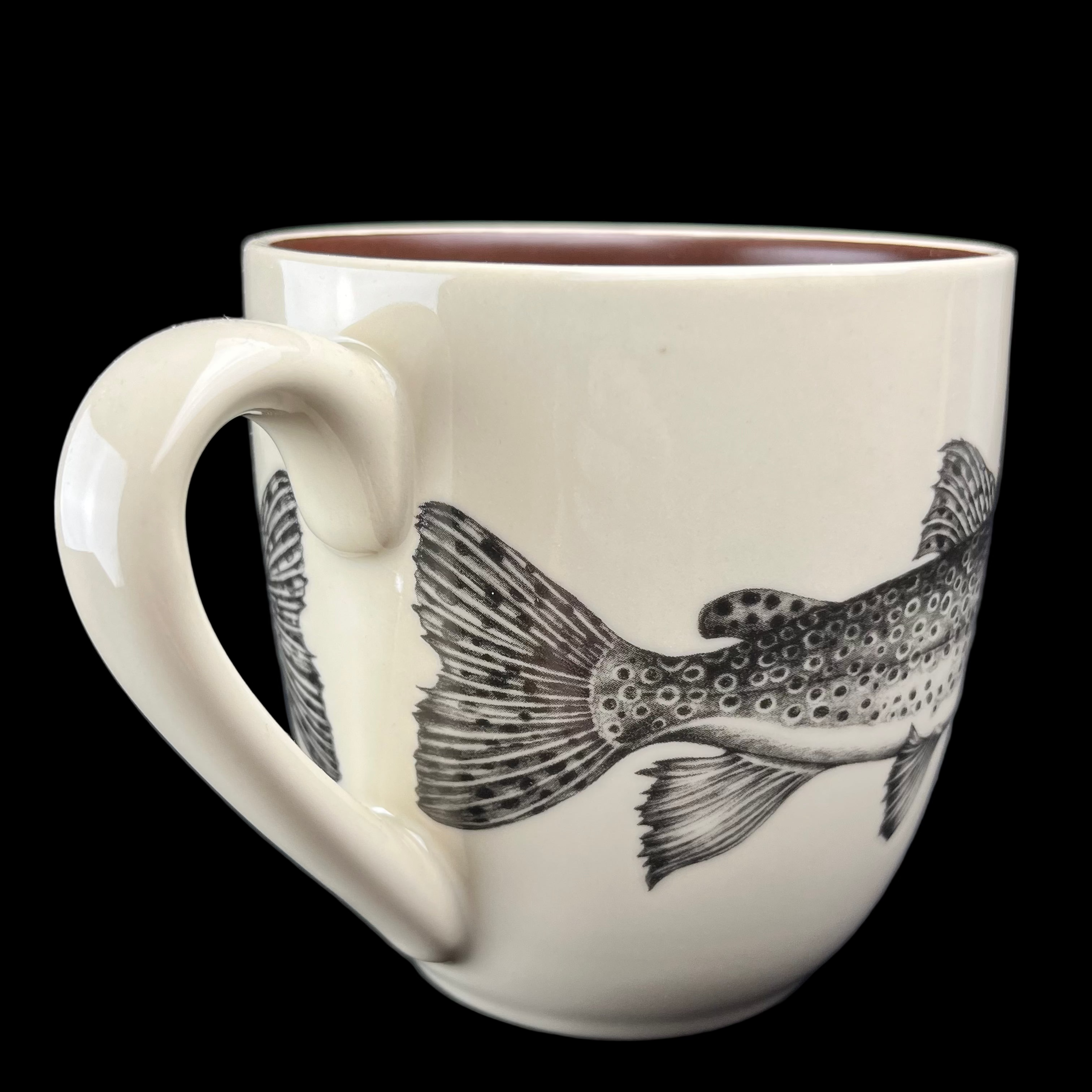 White mug with black fish design on a dark background