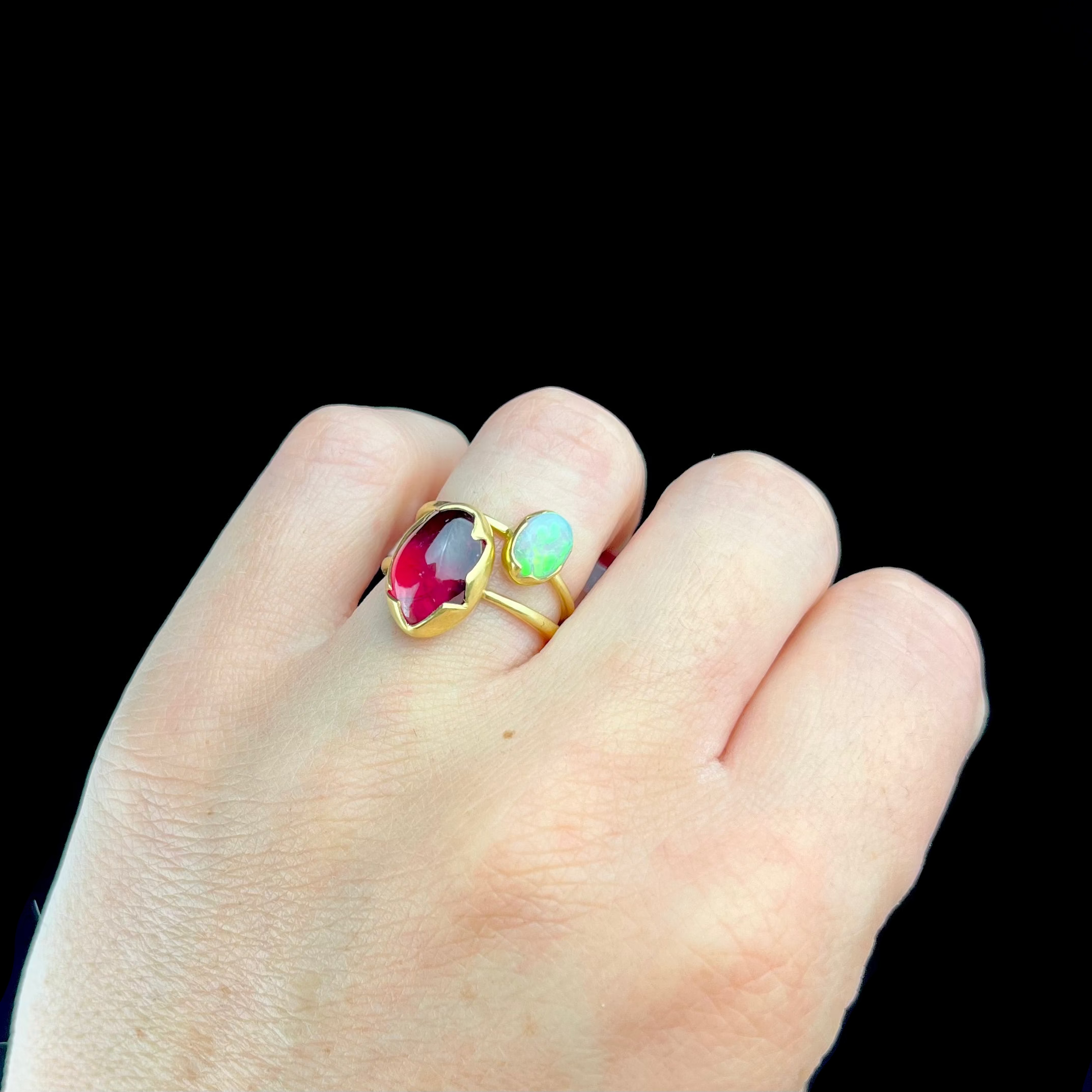 Gold ring with gemstones on a hand against a black background