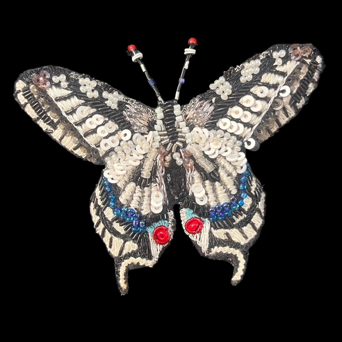 White and black embroidered thread with blue glass bead accents make lifelike realism to swallowtail butterfly 