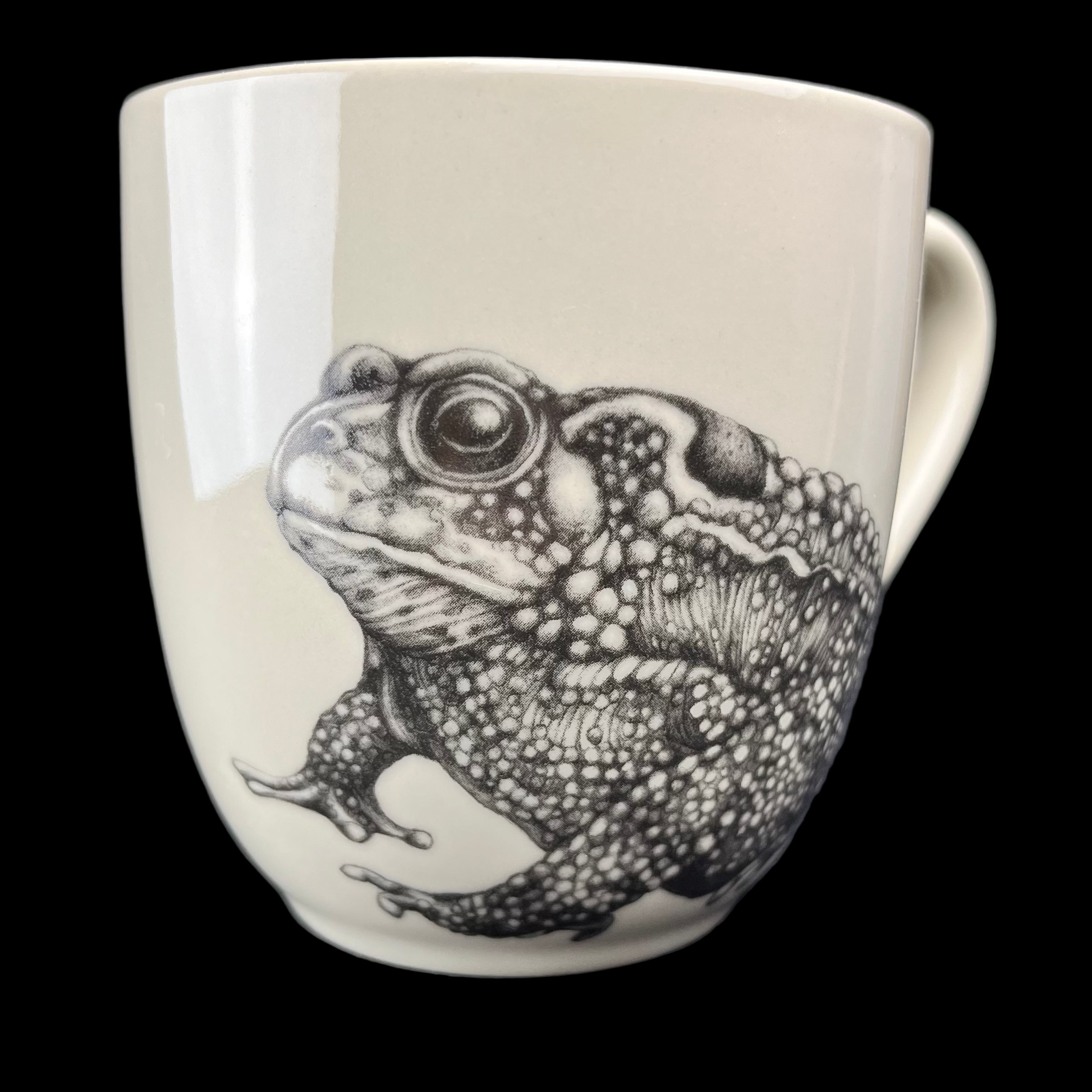 Mug with a black and white frog illustration on a dark surface