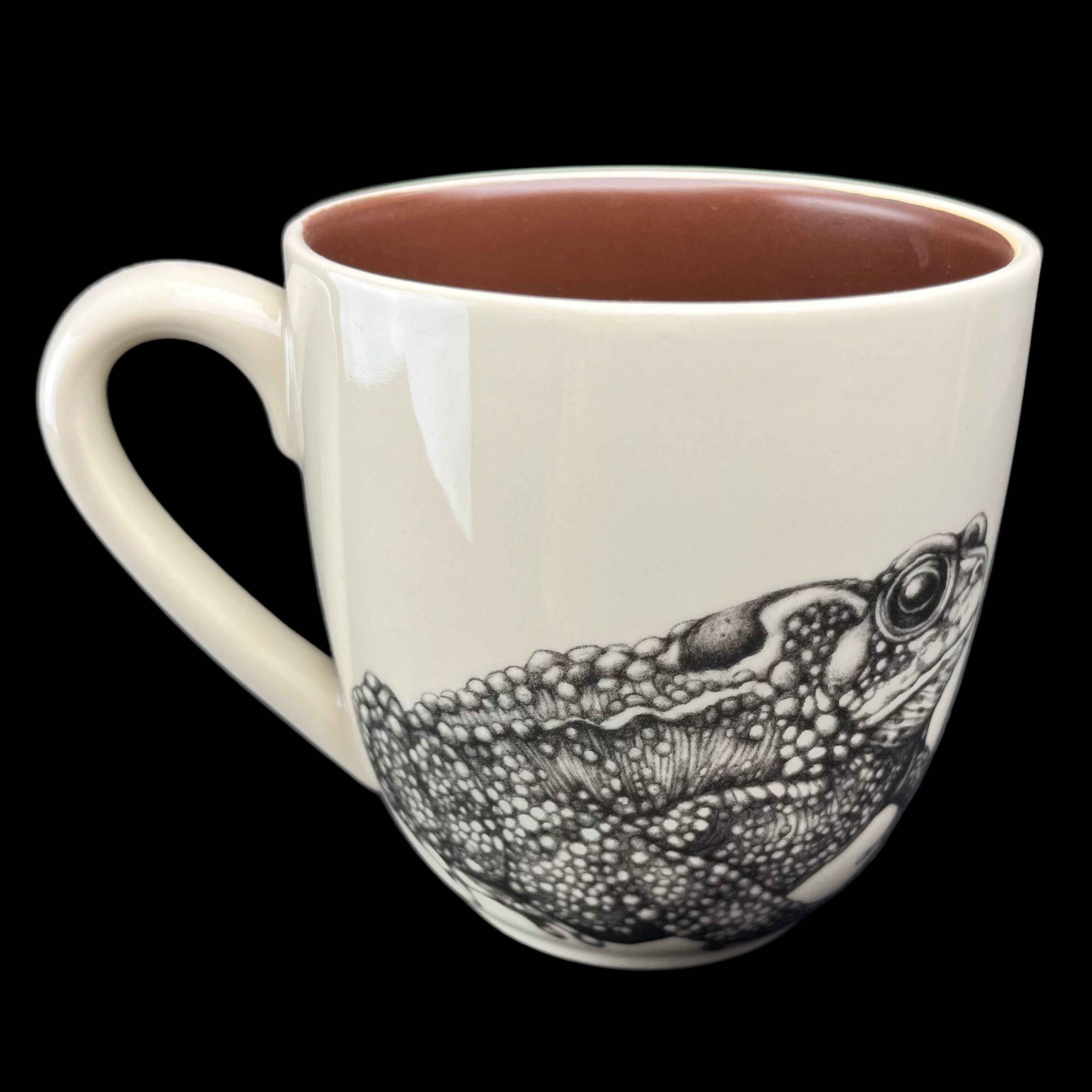 Ceramic mug with a detailed black and white frog illustration on a dark background