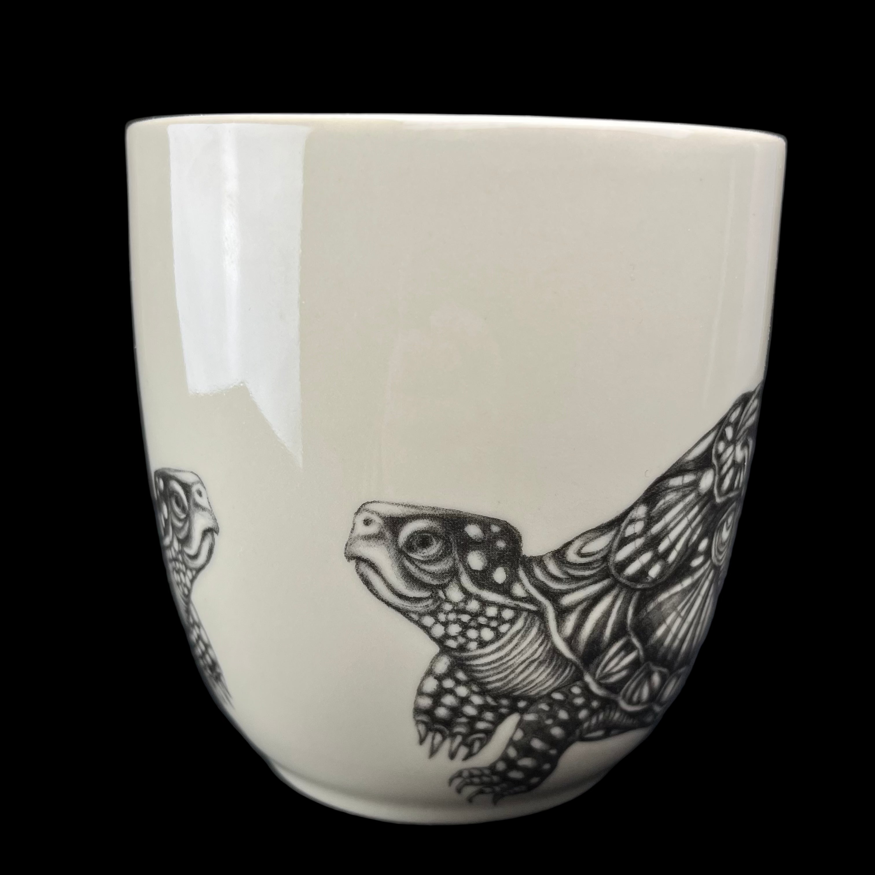 White ceramic mug with black turtle design on a dark background