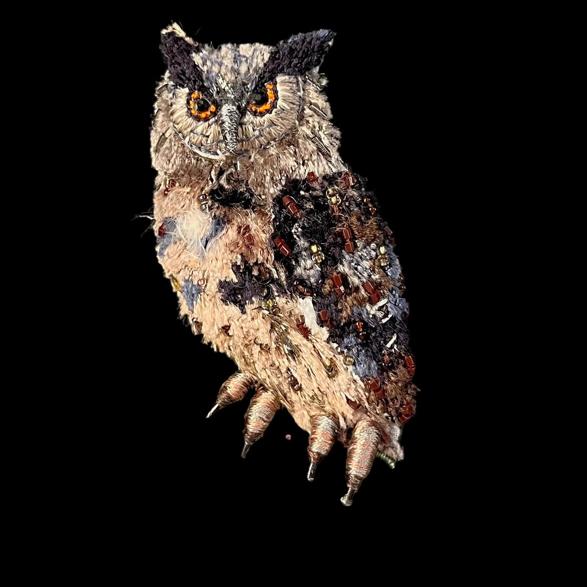 A detailed embroidered owl perched on a branch, shown against a black background with a blue border visible on the right side.