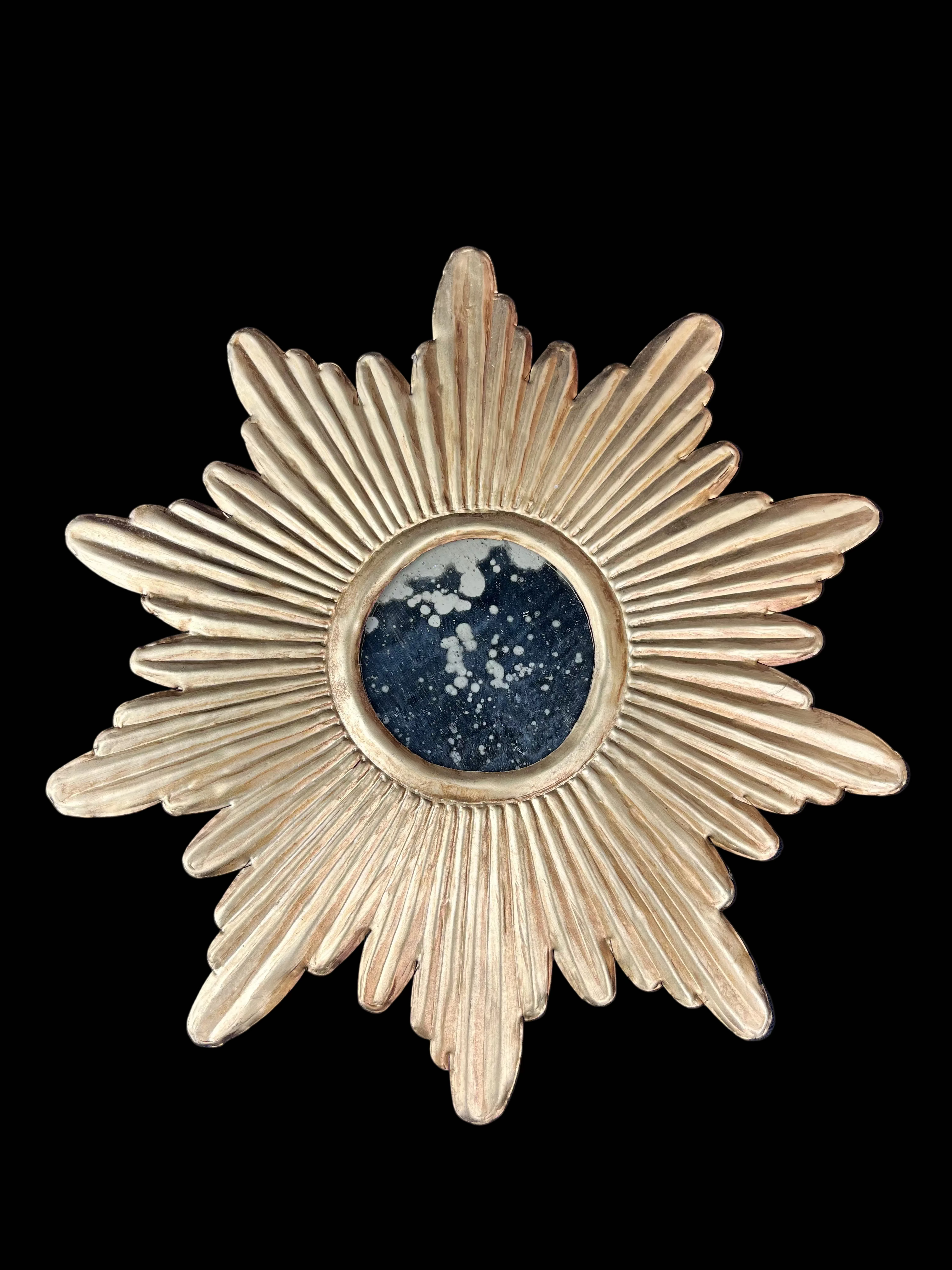 Decorative sunburst mirror with gold finish on a blue background