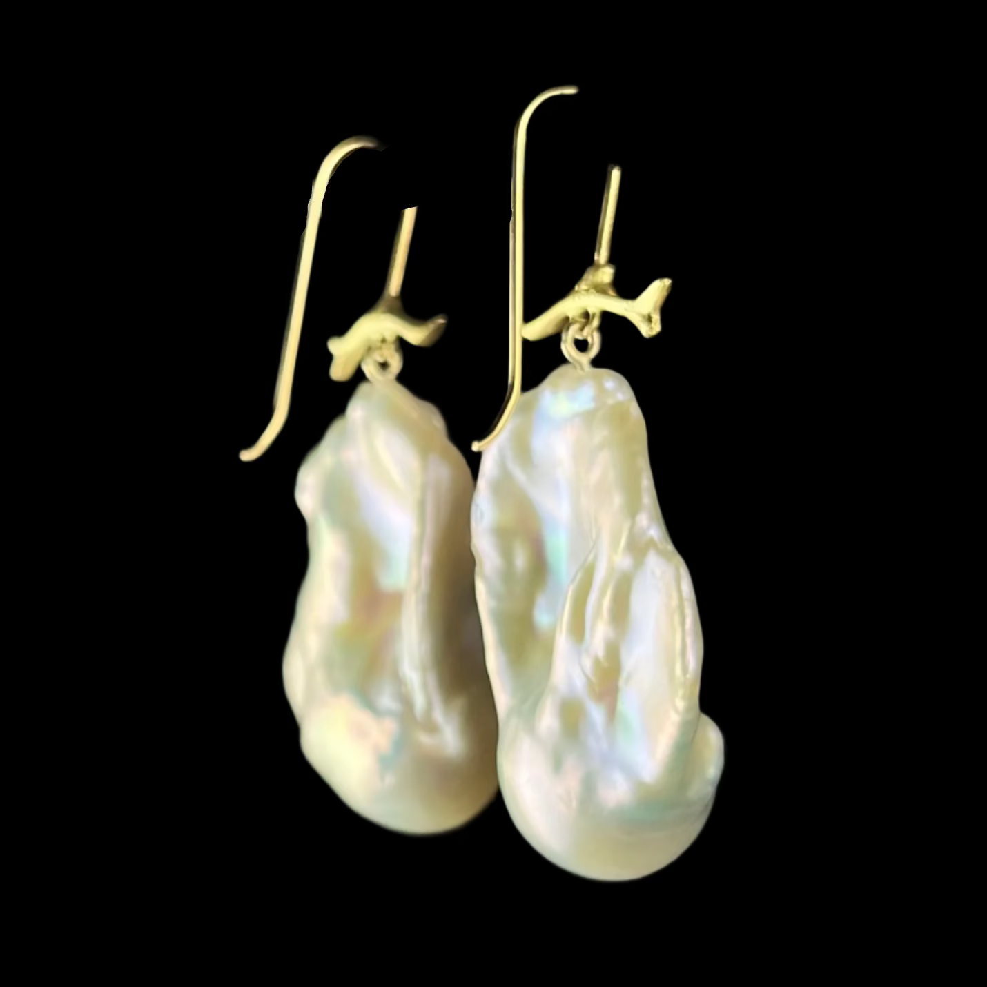 Back view of pearl earrings with gold hooks on a dark background