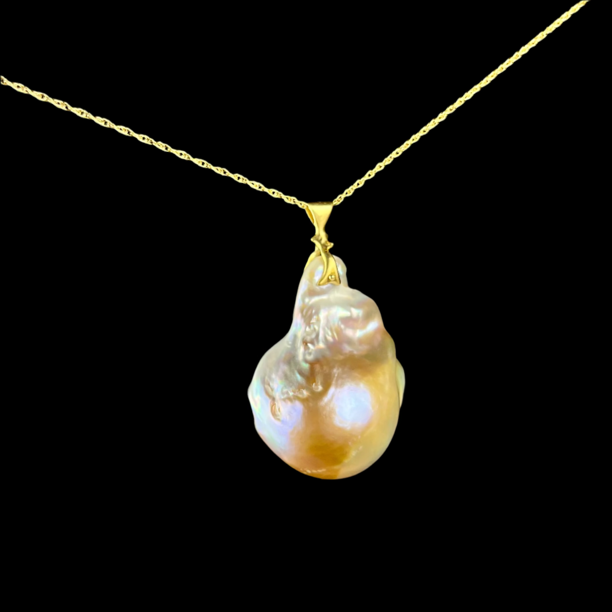 Gold necklace with a large, irregularly shaped pearl pendant on a dark background