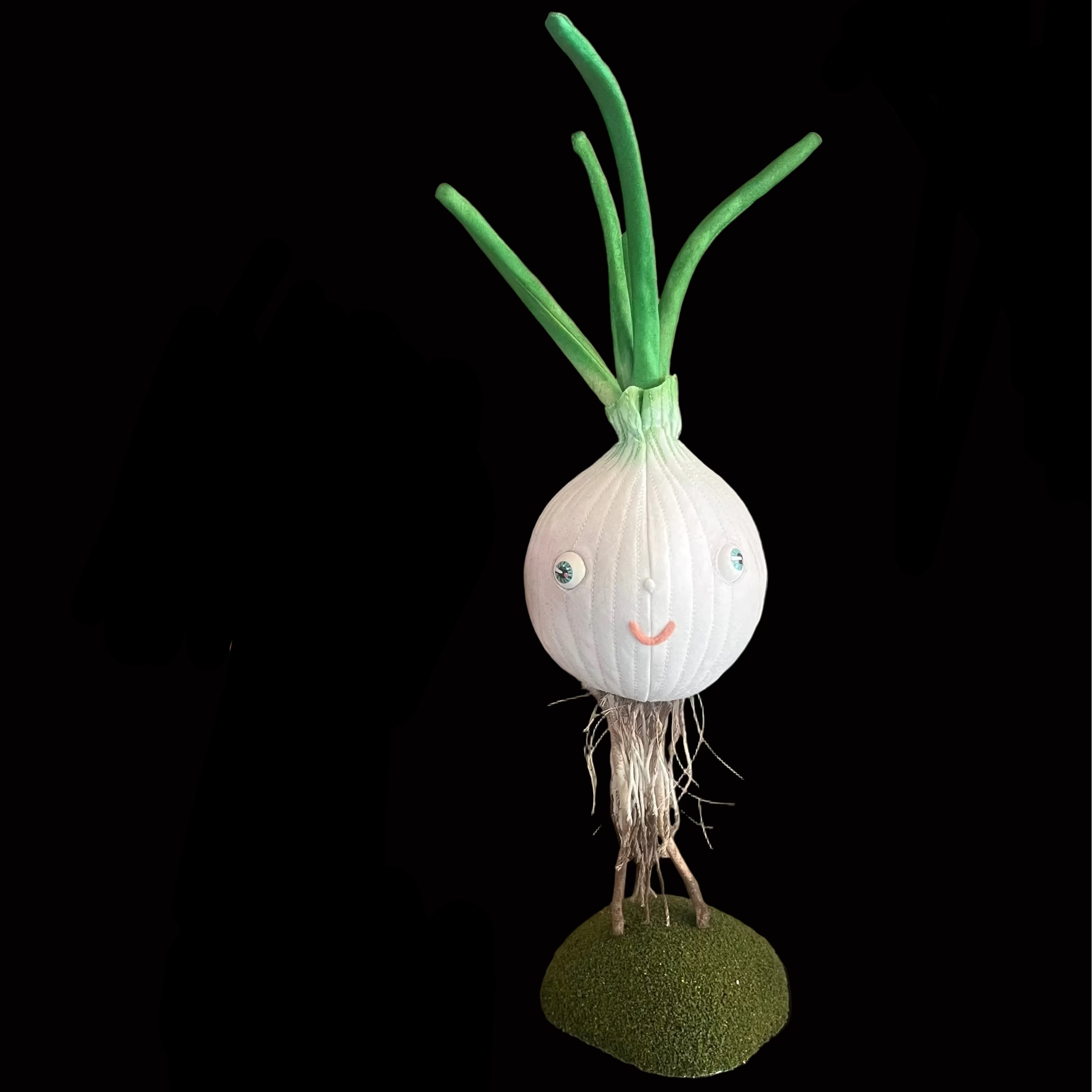 Stuffed fabric white onion sculpture with happy pink lips and bright eyes standing on its roots with green base