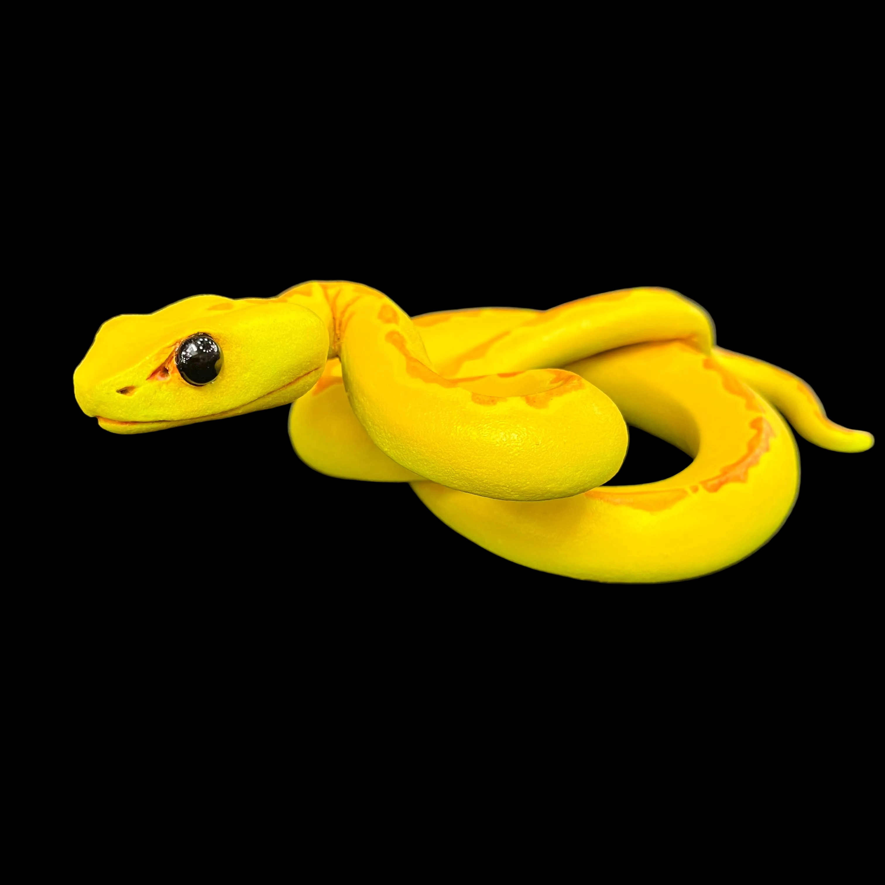 Yellow snake toy on a dark surface with a blurred background