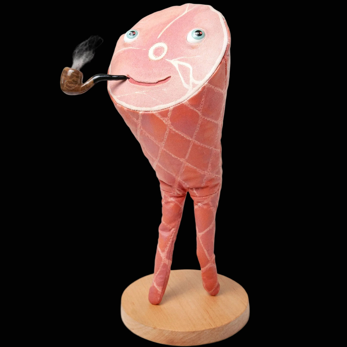 Stuffed smoked ham with legs and painted face with a smoking pipe in its mouth standing on a wooden base.