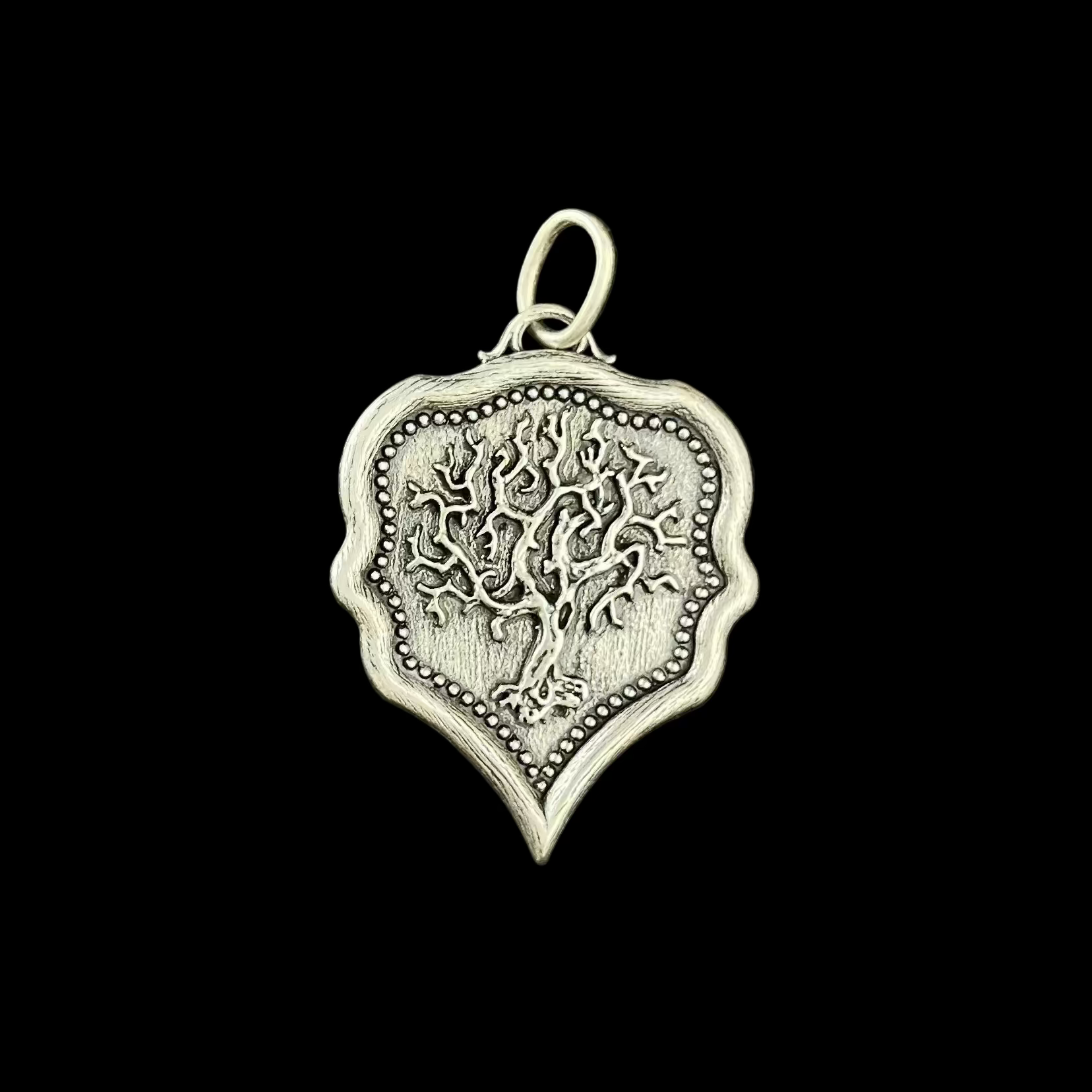 Silver pendant with intricate design on a black background