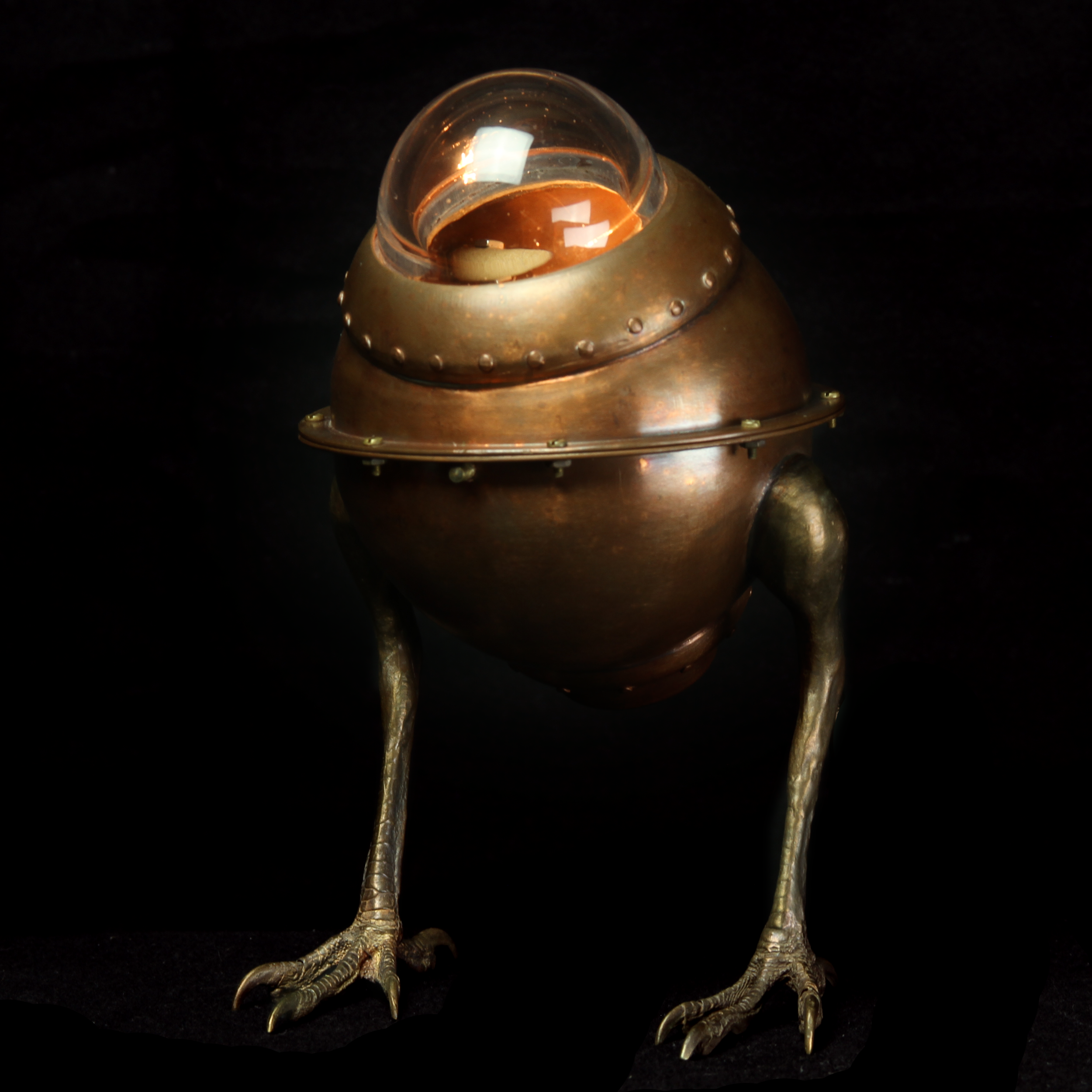 Copper desk lamp with hawk feet on black background