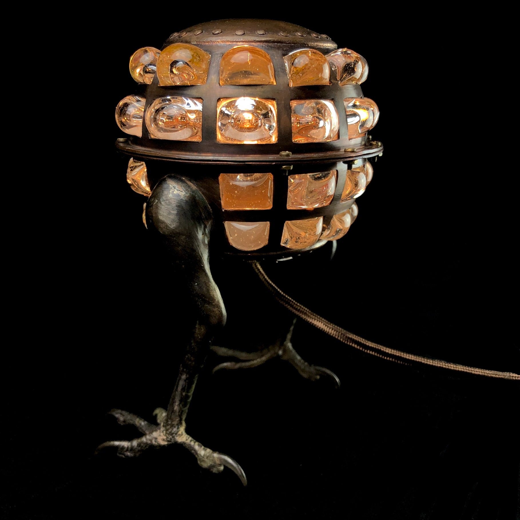 Copper desk lamp with hawk feet on black background