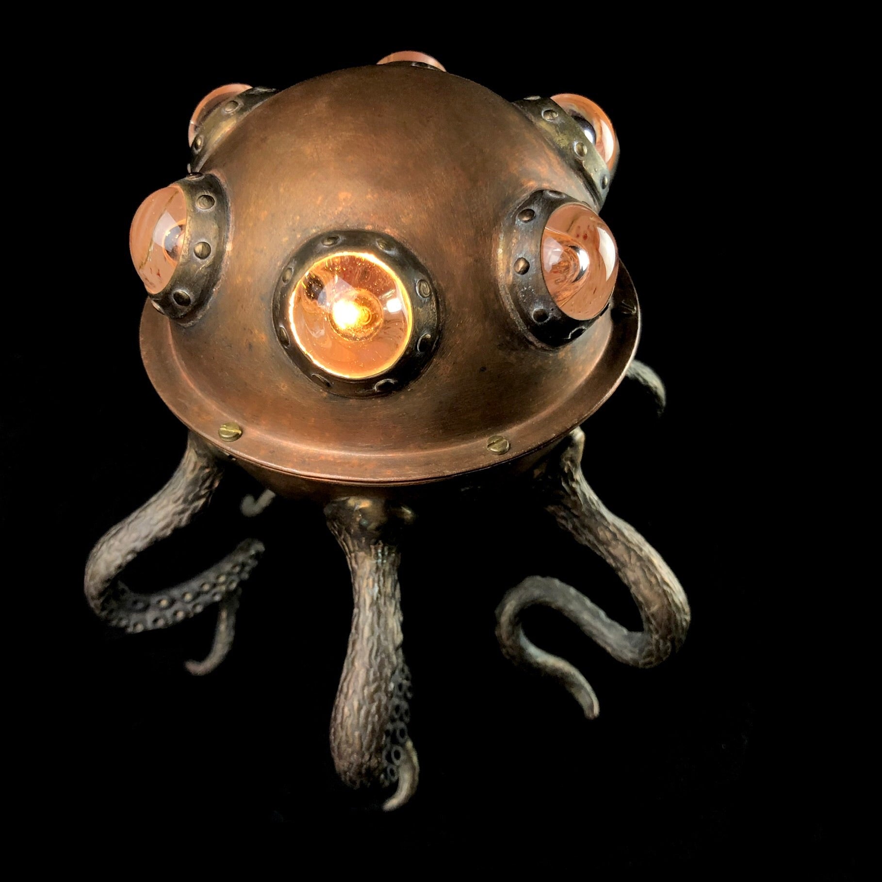 Top view of desk lamp with glass accents and tentacles on black background