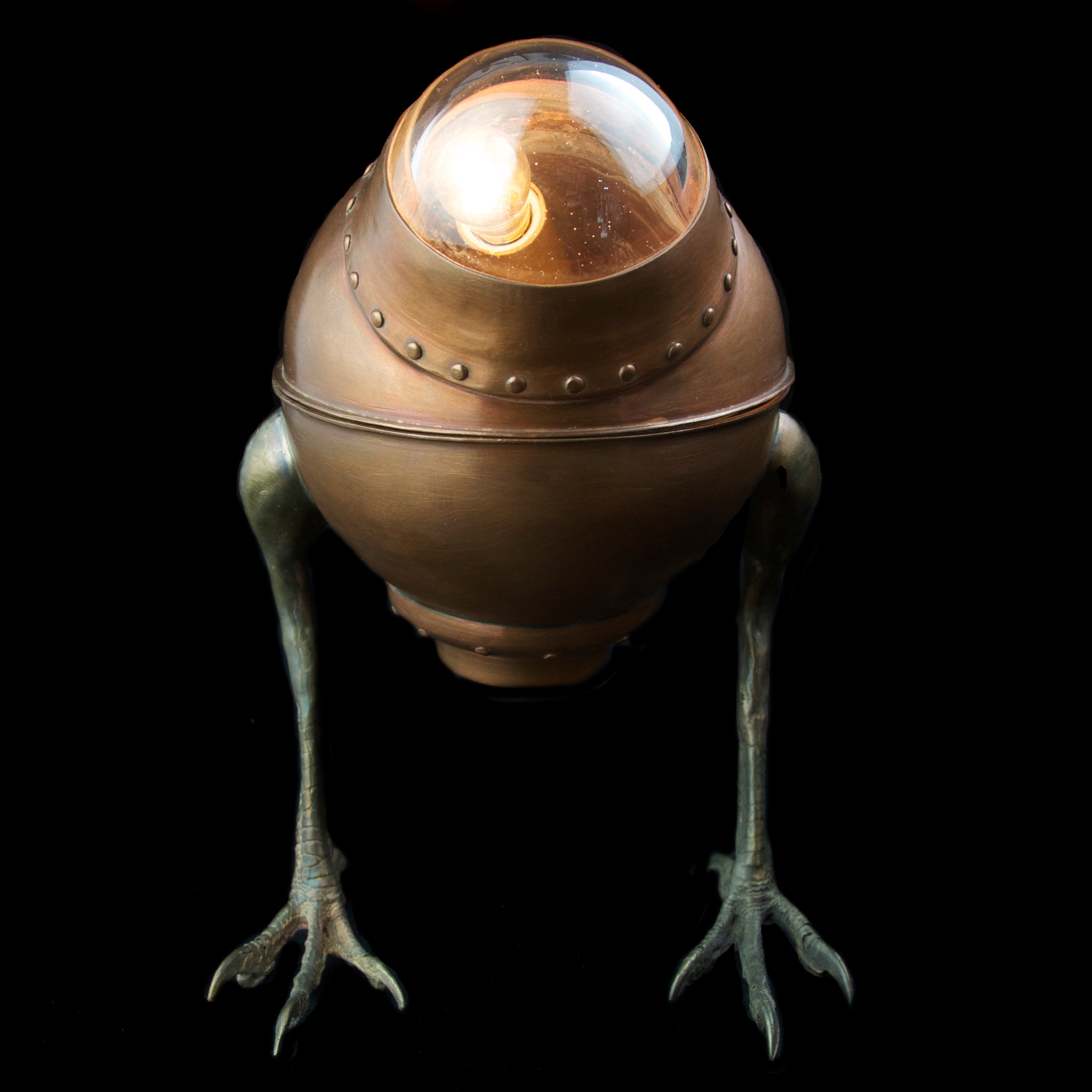 Copper desk lamp with hawk feet on black background