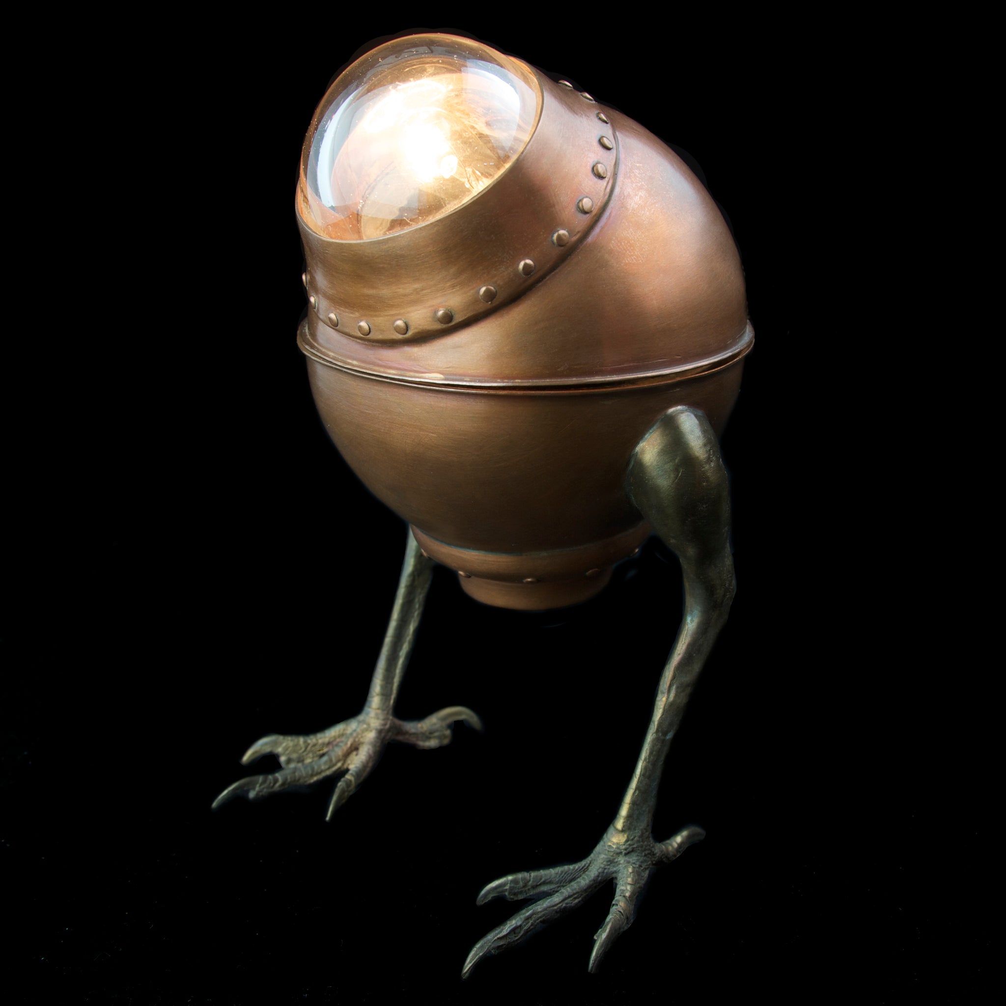 Copper desk lamp with hawk feet on black background