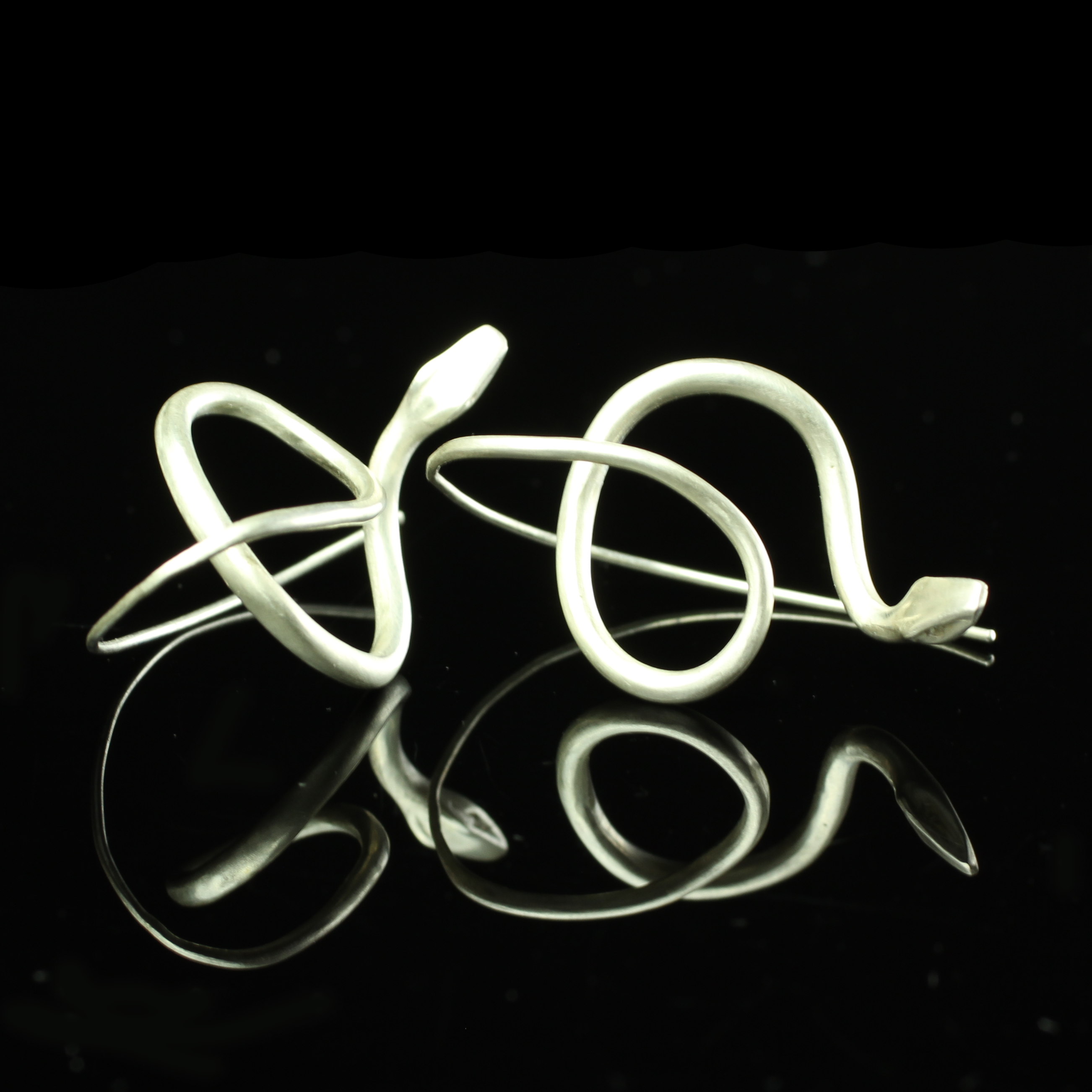 Sterling Silver Snake Earrings resting side by side with reflection below