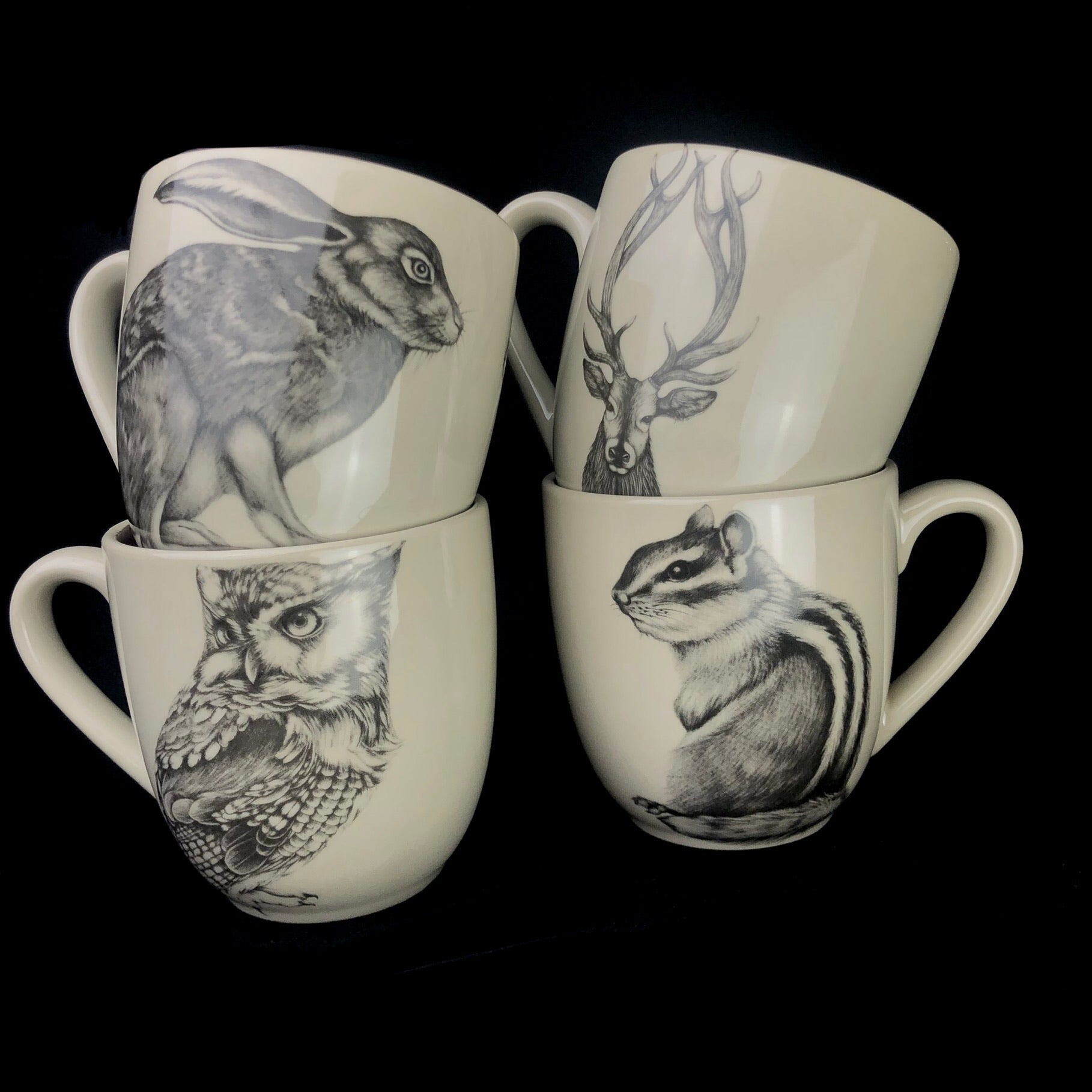 A set of four mugs, including the Buck Mug, with drawings of animals found in the forest.  Rabbit, Owl and Chipmunk.