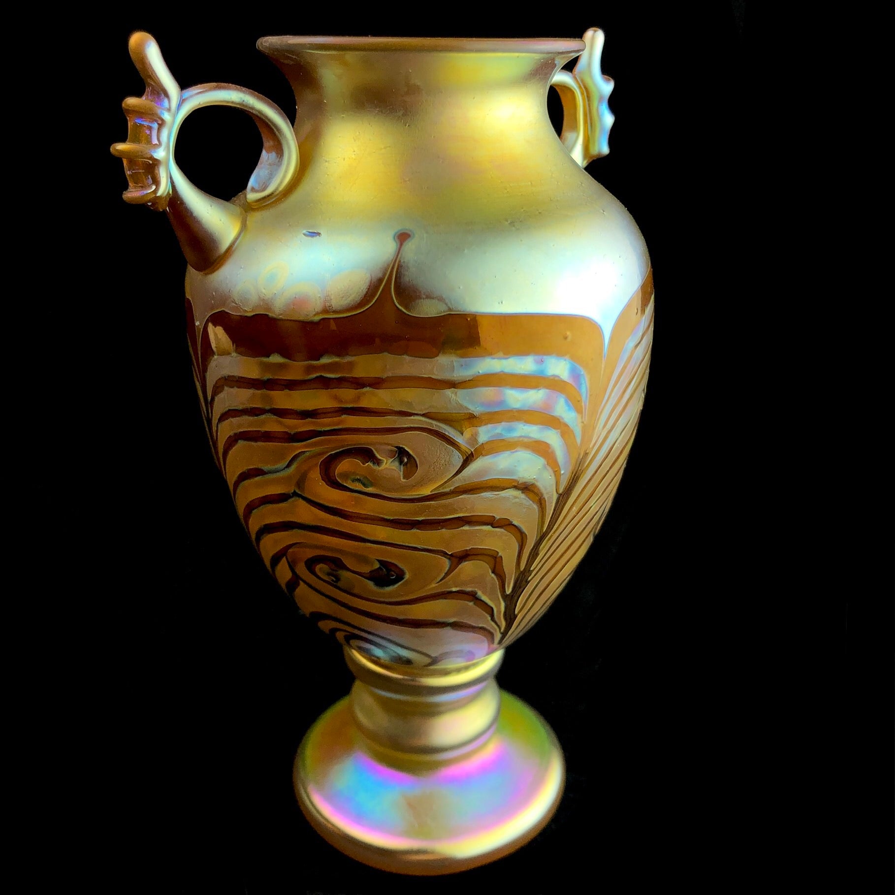 Side view of iridescent yellow vase with feather shaped decoration and color variation in glass