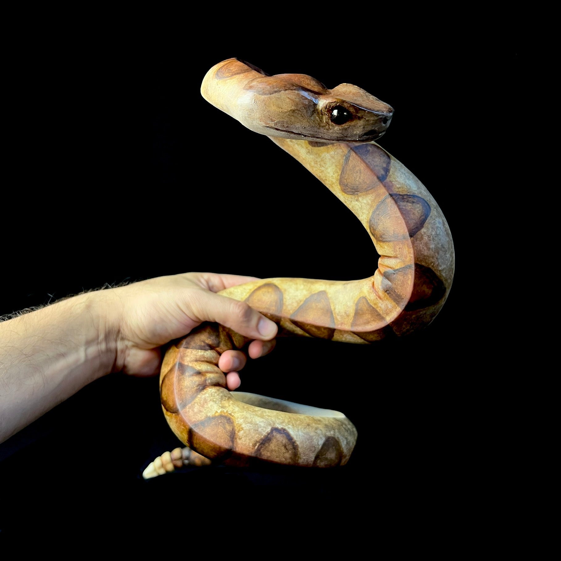 Front view of snake sculpture held by a hand for size 