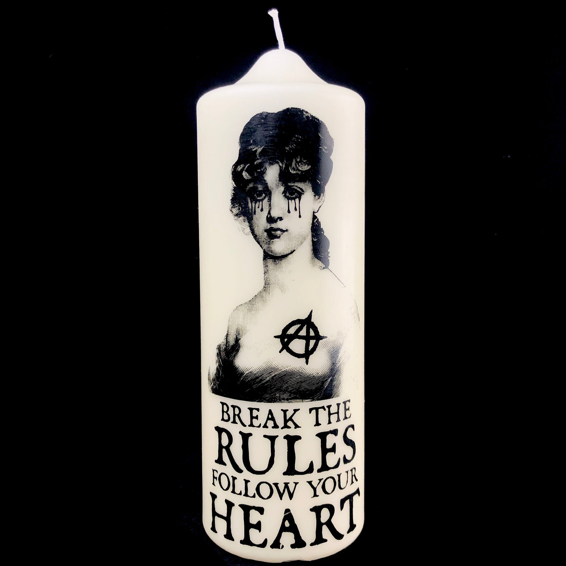 uncented pillar candle made in italy with printed black image and the words "break the rules follow your heart"
