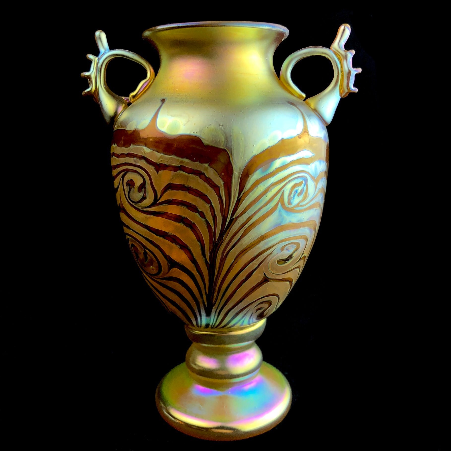 Front view of iridescent yellow glass vase shaped like an urn with small handles toward the top